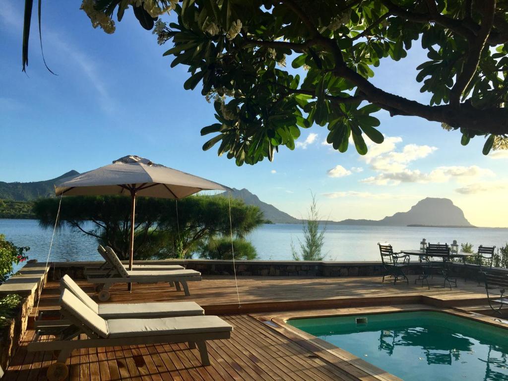 a swimming pool with an umbrella and chairs next to the water at Harmonie in Rivière Noire