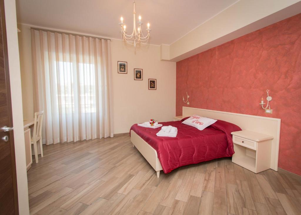 sypialnia z łóżkiem i czerwoną ścianą w obiekcie B&B Vista Santuario w Syrakuzach