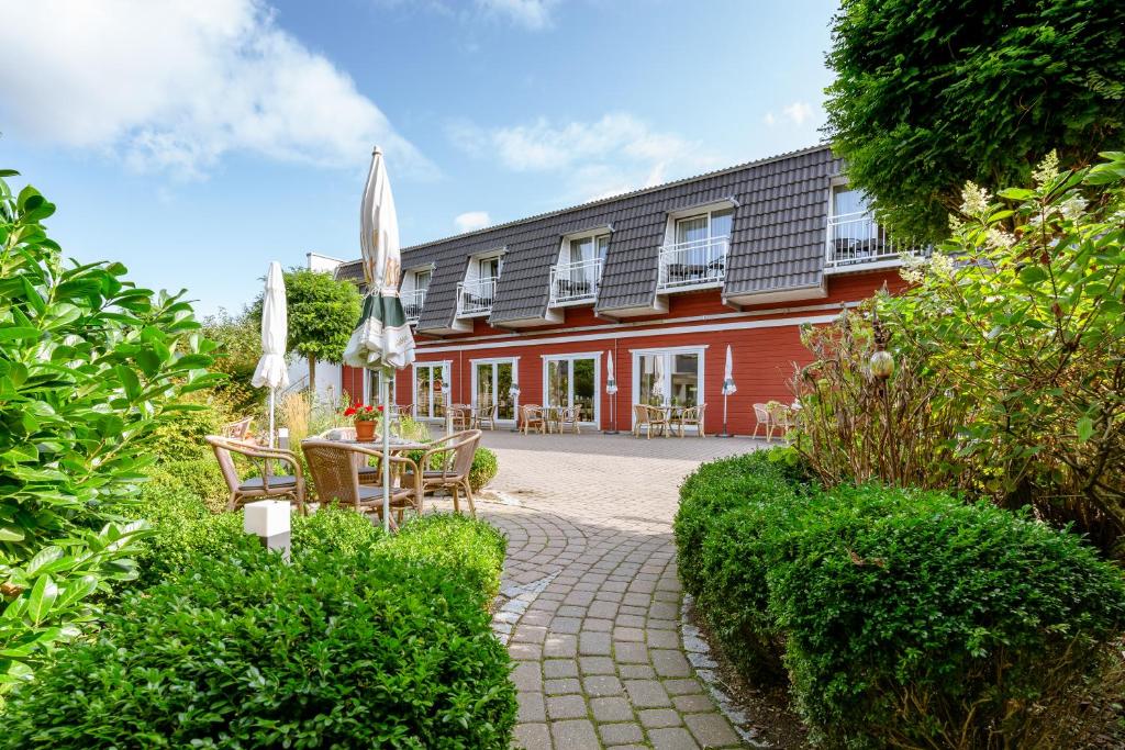 a red building with a patio with a table and chairs at Hotel am Schlosspark garni in Husum