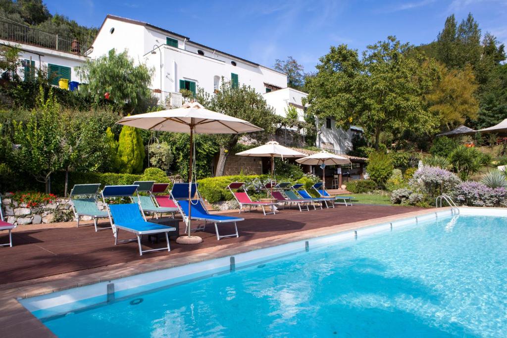 - une piscine avec des chaises et des parasols à côté d'un bâtiment dans l'établissement Agriturismo Villa Lupara, à Salerne