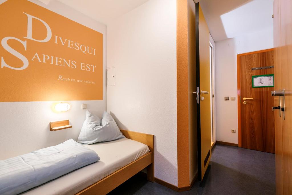 a small room with a bed with a sign on the wall at Jugendherberge Regensburg in Regensburg