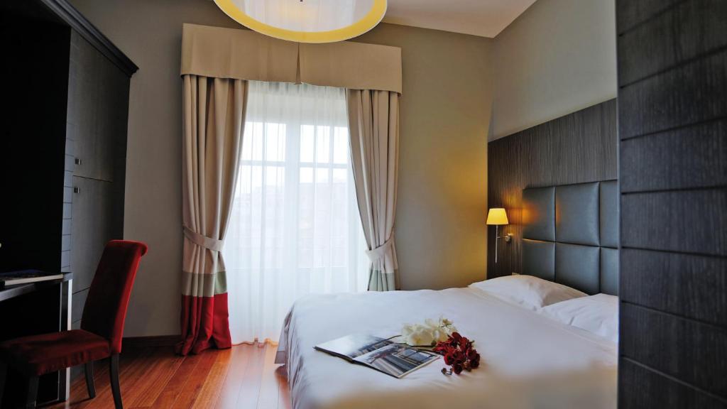 ein Hotelzimmer mit einem Bett und einem Fenster mit Blumen darauf in der Unterkunft Hotel Porta Felice & Spa in Palermo