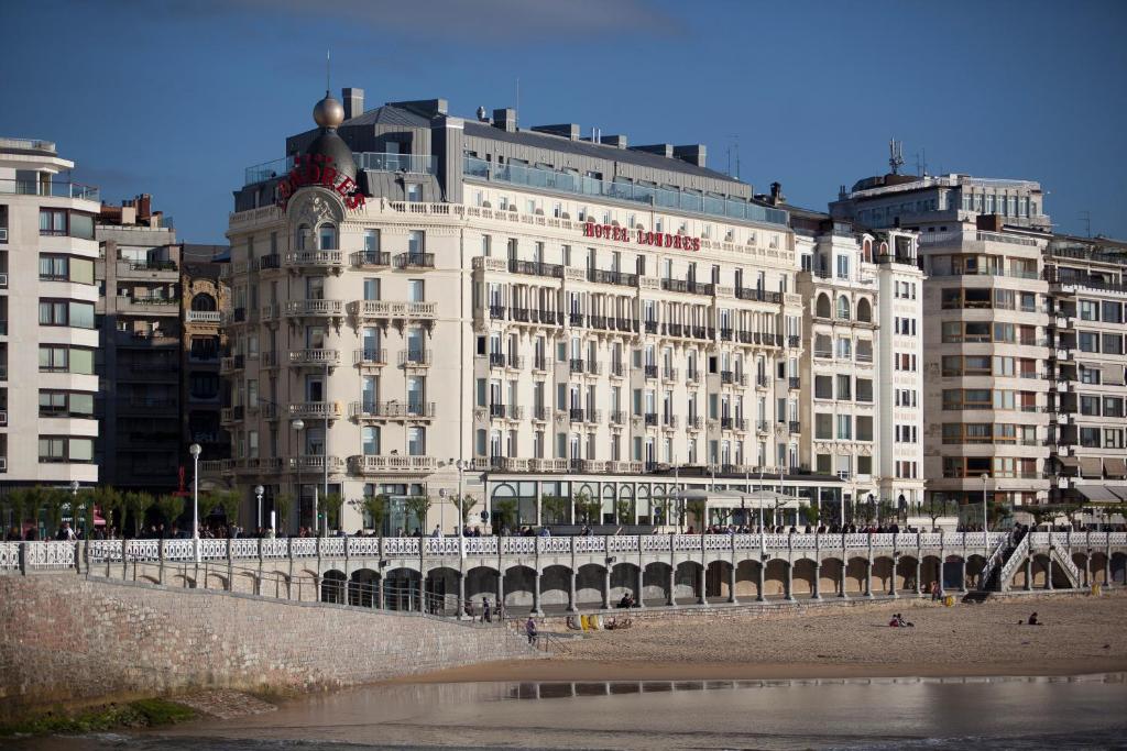 un gran edificio blanco en la playa con edificios en Hotel de Londres y de Inglaterra en San Sebastián