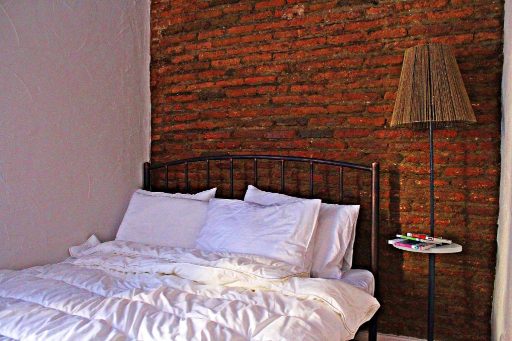 uma cama num quarto com uma parede de tijolos em Maria's homestay em Tbilisi