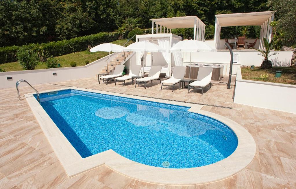 a swimming pool with chairs and umbrellas and a table at Villa Garden Apartment with Pool Opatija in Opatija