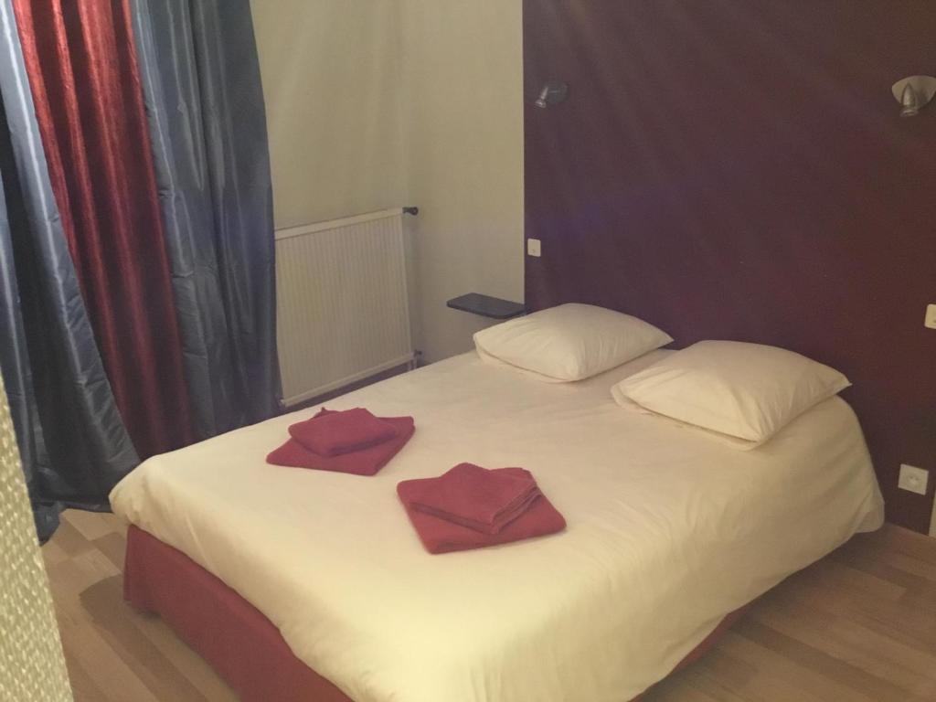 Una cama blanca con dos almohadas rojas. en La Châtaigneraie en Uzer