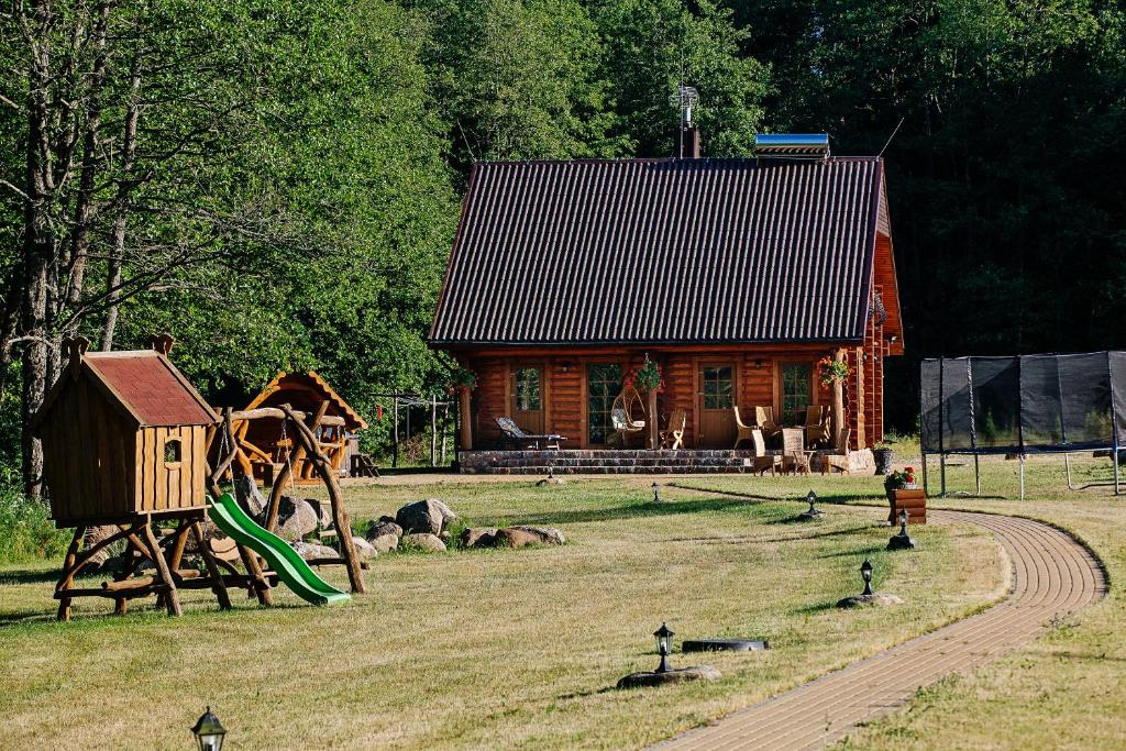 a log cabin with a playground in front of a house at Vila "Laumių lankos" in Plateliai