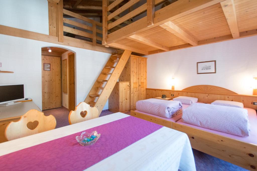 a bedroom with two beds and a ladder at Hotel Soliva in Sedrun