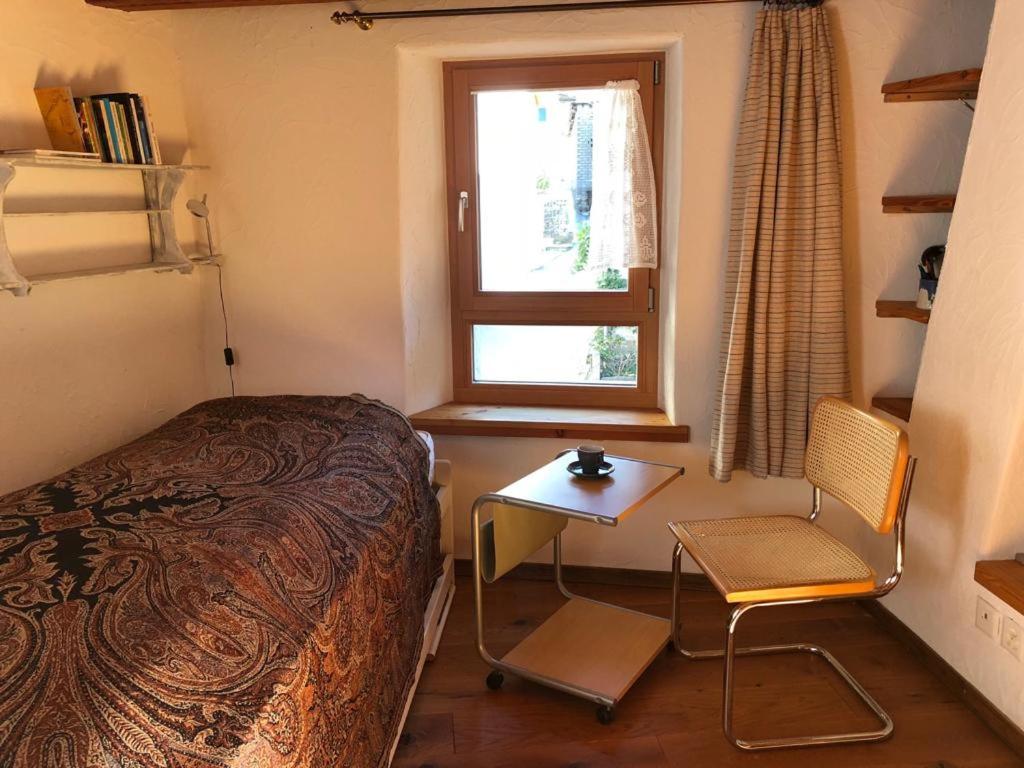 Schlafzimmer mit einem Bett, einem Tisch und einem Fenster in der Unterkunft Rustico Cadrobi 20 in San Vittore