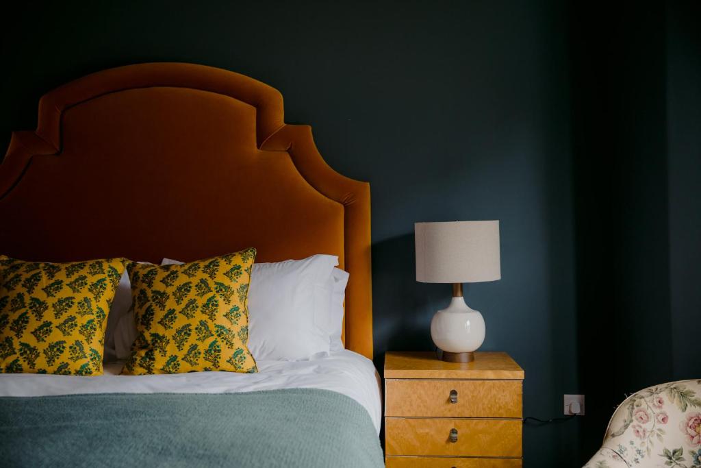 a bedroom with a bed with a wooden headboard and a lamp at The Rose in Deal