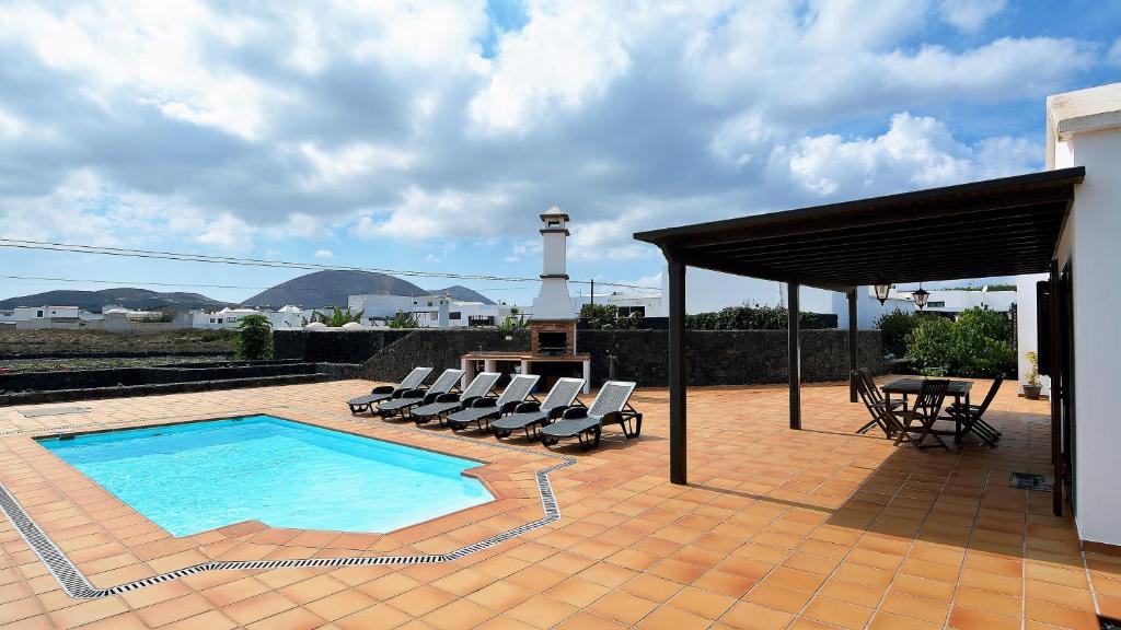 ein Pool mit Stühlen und ein Leuchtturm im Hintergrund in der Unterkunft Villa Deluxe Campesina Private Pool in San Bartolomé