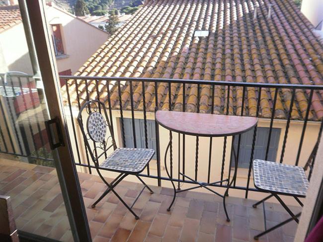einen Balkon mit einem Tisch und 2 Stühlen sowie ein Gebäude in der Unterkunft 6SOL16 Appartement duplex proche mer in Collioure