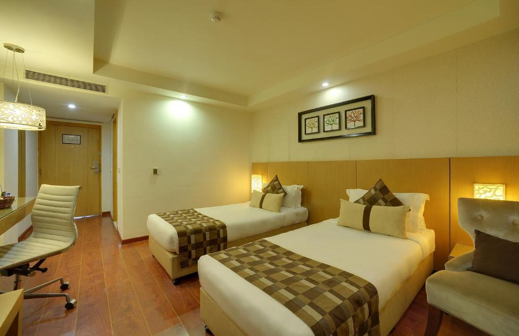 a hotel room with two beds and a desk and a chair at Siamton Inn- A Cygnett Collection in Kolkata