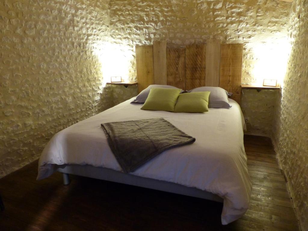 1 dormitorio con 1 cama con sábanas blancas y almohadas verdes en Têtes à l'air, en Montils