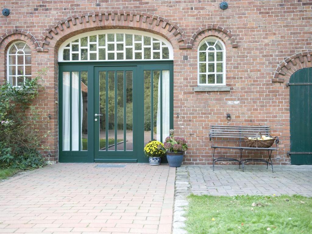 a green door on a brick building with a bench at Hürhus Hude in Hude