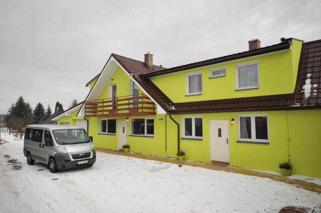 een busje geparkeerd voor een geel huis bij Apart-Bungalovy Gitka in Mlynčeky