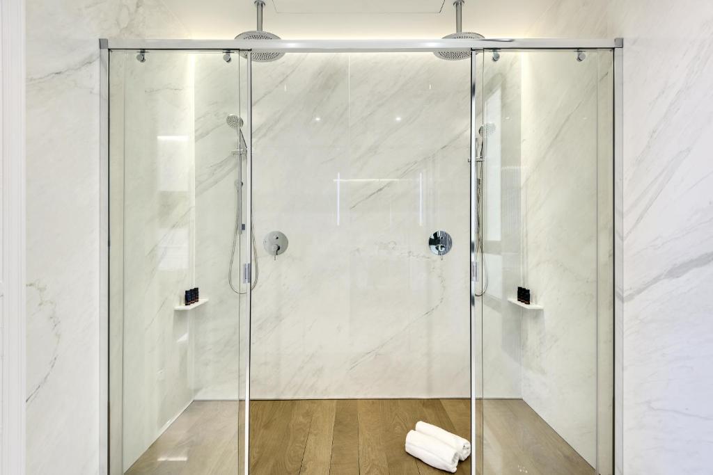 a bathroom with a shower stall and a tub at Boutique Hotel H10 Villa de la Reina in Madrid