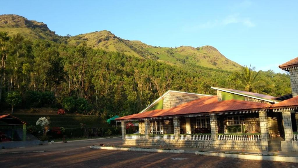 ein Gebäude mit einem Berg im Hintergrund in der Unterkunft Foothills Homestay in Chikmagalur