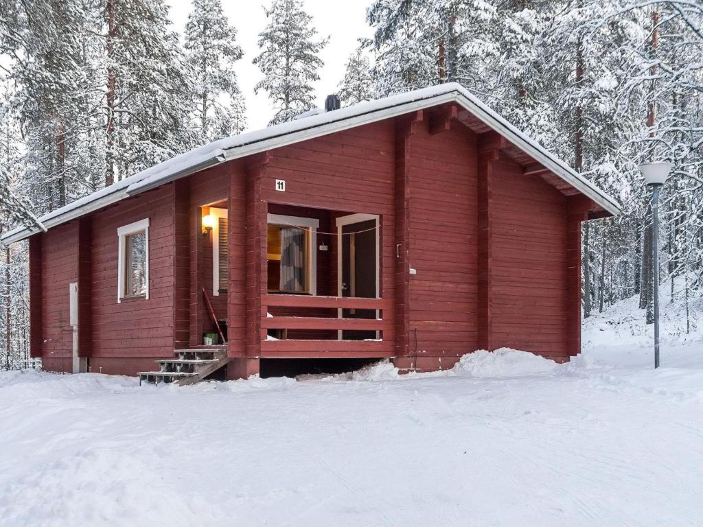 a small red cabin in the snow with trees at Holiday Home Viipusjärvi 11 by Interhome in Ruka
