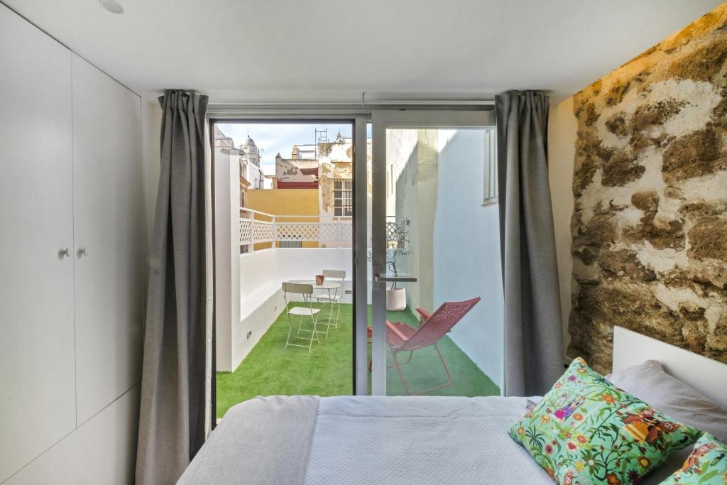 a bedroom with a bed and a balcony with a table at Casa La Muralla MEDIEVAL by Cadiz4Rentals in Cádiz