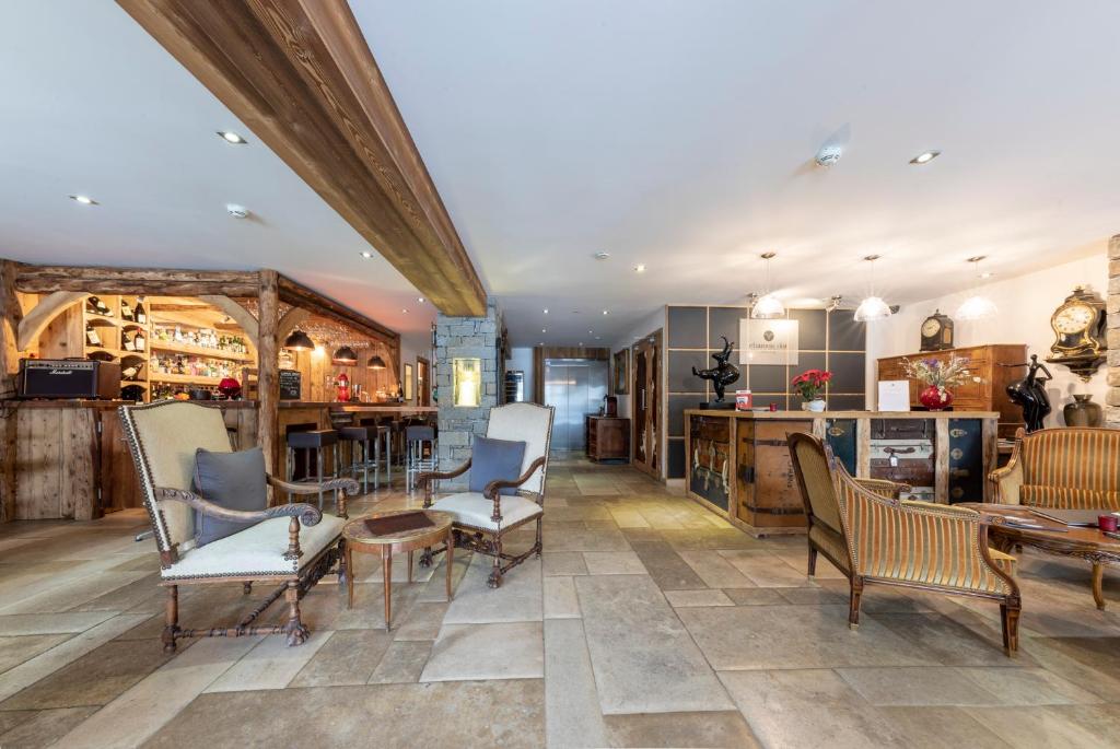 a living room with chairs and tables and a kitchen at Chamois d'Or Hotel in Les Gets