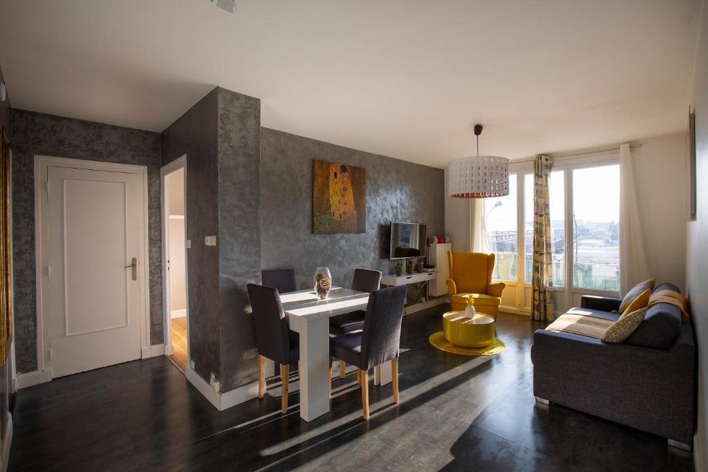 uma sala de estar com uma mesa e cadeiras e um sofá em Appartement Malya & parking privé em Grenoble
