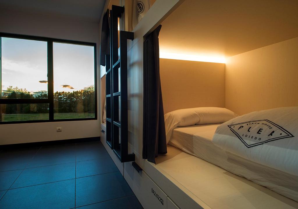a bedroom with a bed and a large window at Plea Beach House in Loredo
