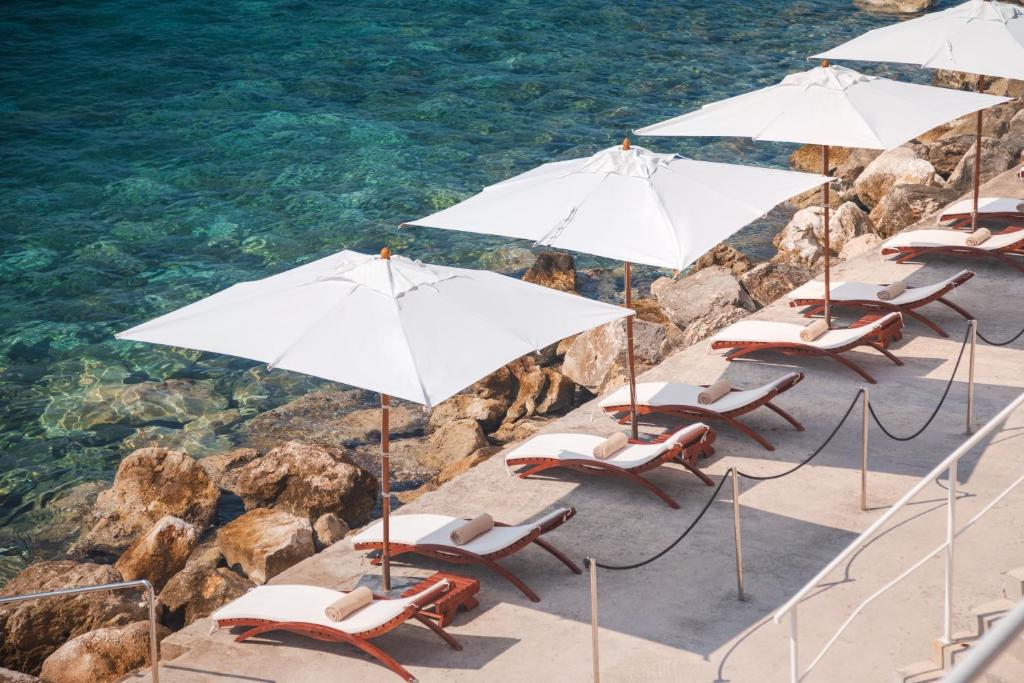 a group of chairs and umbrellas on the beach at Sun Gardens Dubrovnik in Dubrovnik