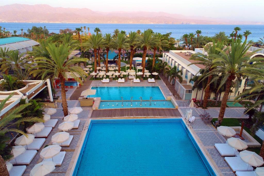 
a beach with a pool, chairs, and a pool table at Yam Suf by Isrotel Collection in Eilat
