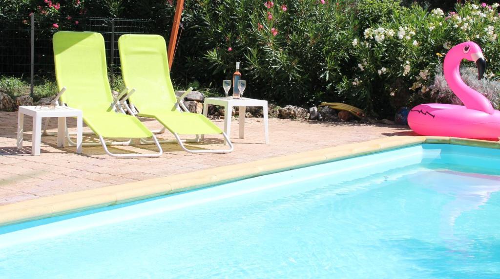 a group of lawn chairs and a pink flamingo next to a pool at Le Petit Paradis - La Provençale in Lorgues
