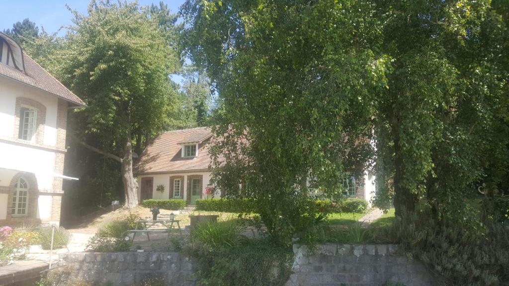 una casa con un árbol y una pared de piedra en Le Moulin de Longueil, en Longueil
