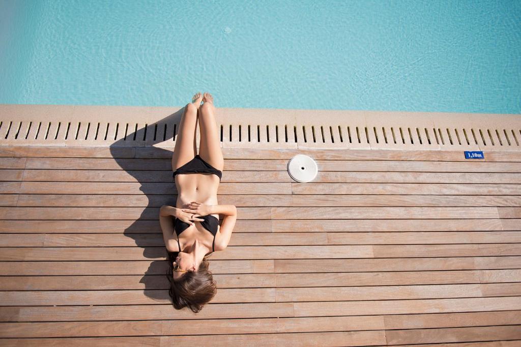 a woman laying on the side of a swimming pool at Las Gaviotas Suites Hotel & Spa in Playa de Muro