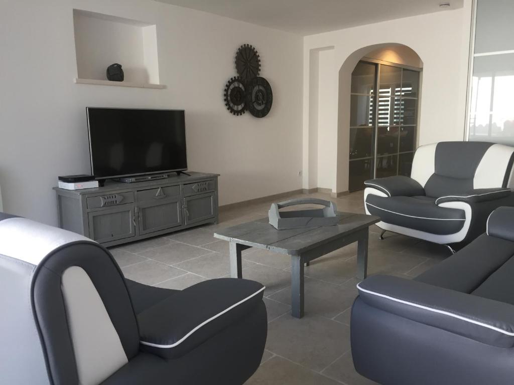 a living room with couches and a tv and a table at La rose trémière in Rivedoux-Plage