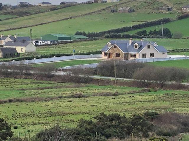 a house in the middle of a green field at Beautiful Home on Lake Carrowmore in Belmullet