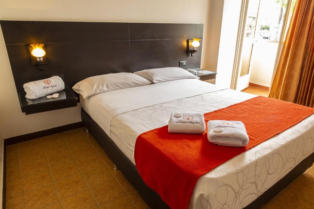 a bedroom with a bed with two towels on it at Hotel Iguazu in Villavicencio