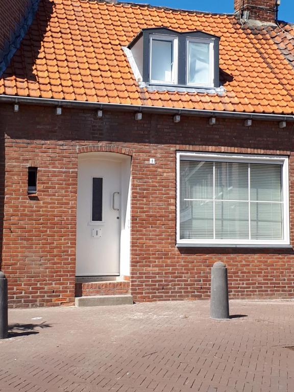 a brick house with a white door and windows at markt 1 in Biervliet