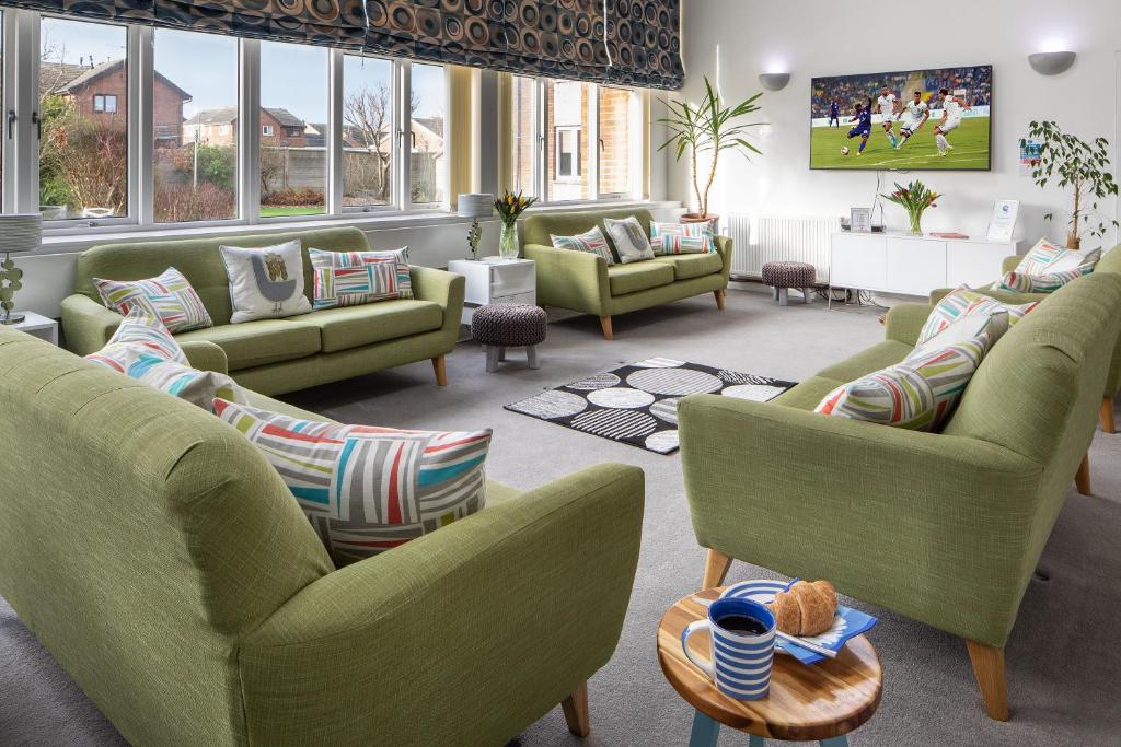 a living room with green chairs and couches at West Point House in Barrow in Furness