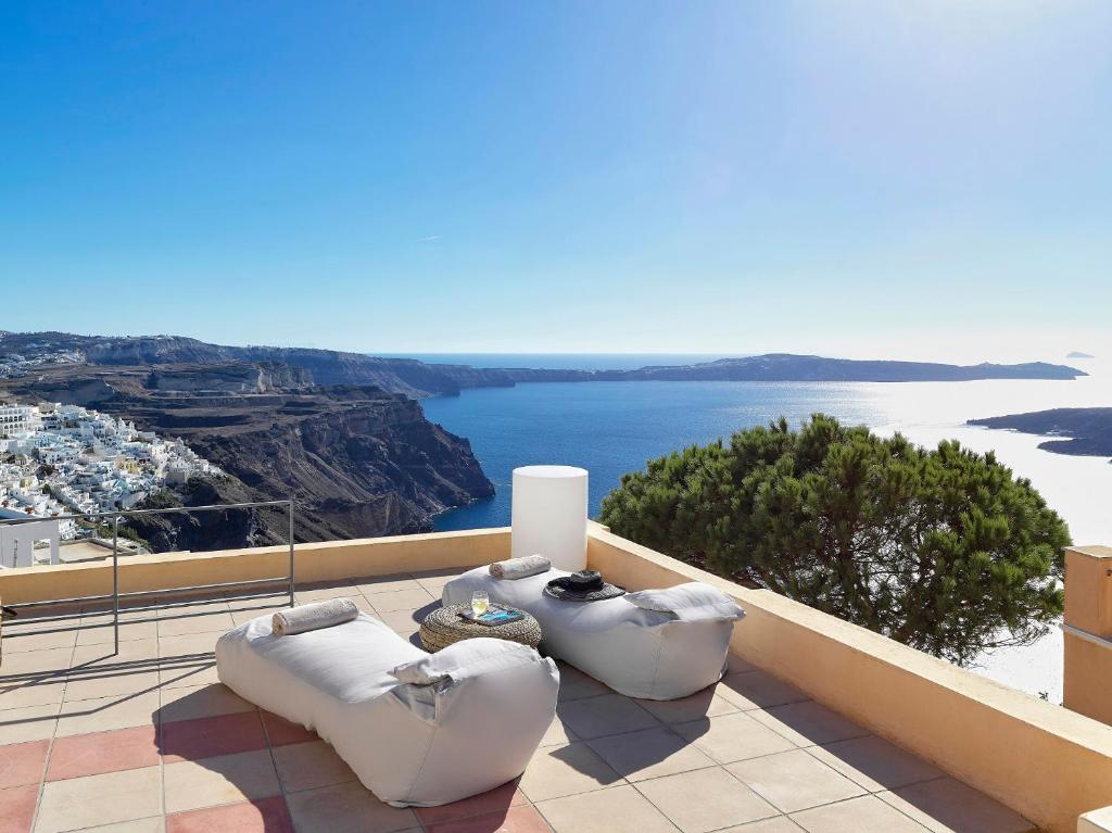 a balcony with white chairs and a view of the water at Archipel Mansion in Fira