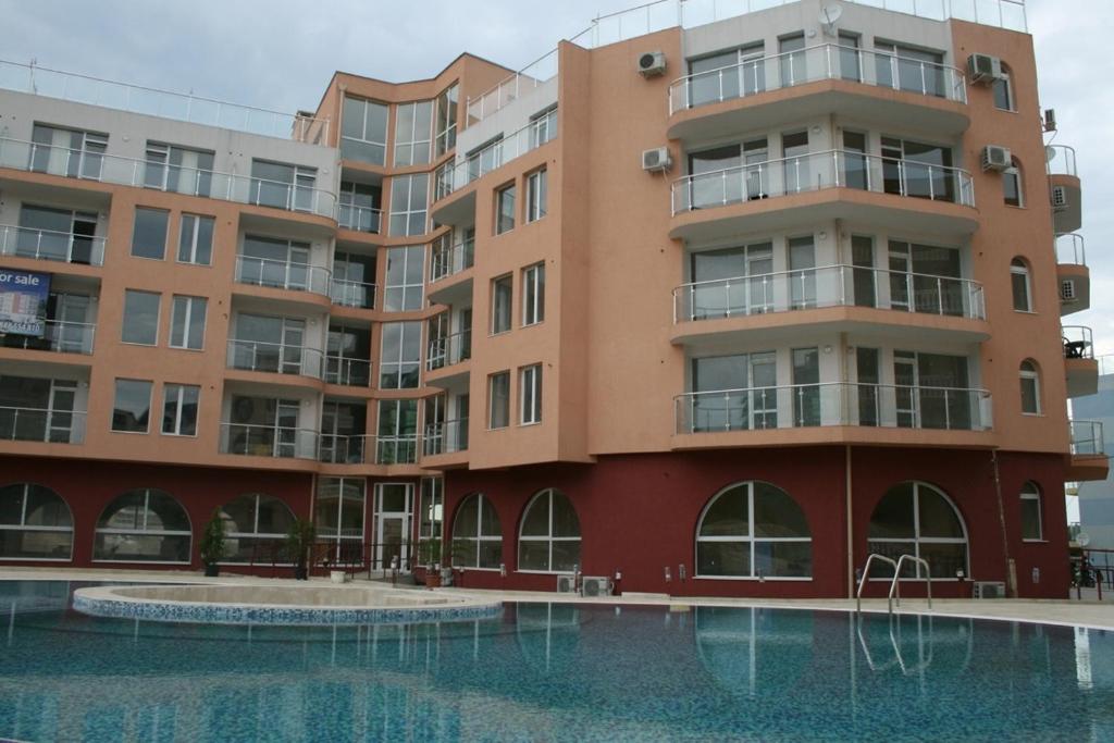an apartment building with a swimming pool in front of it at Apartments Perla Beach - Ivanovi in Primorsko