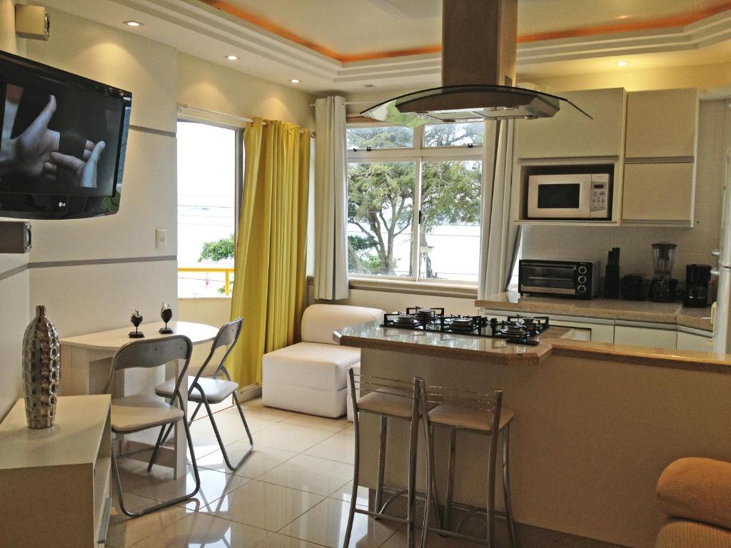 cocina y sala de estar con mesa y sillas en ILHAS CANARIAS APTO 101, en Florianópolis