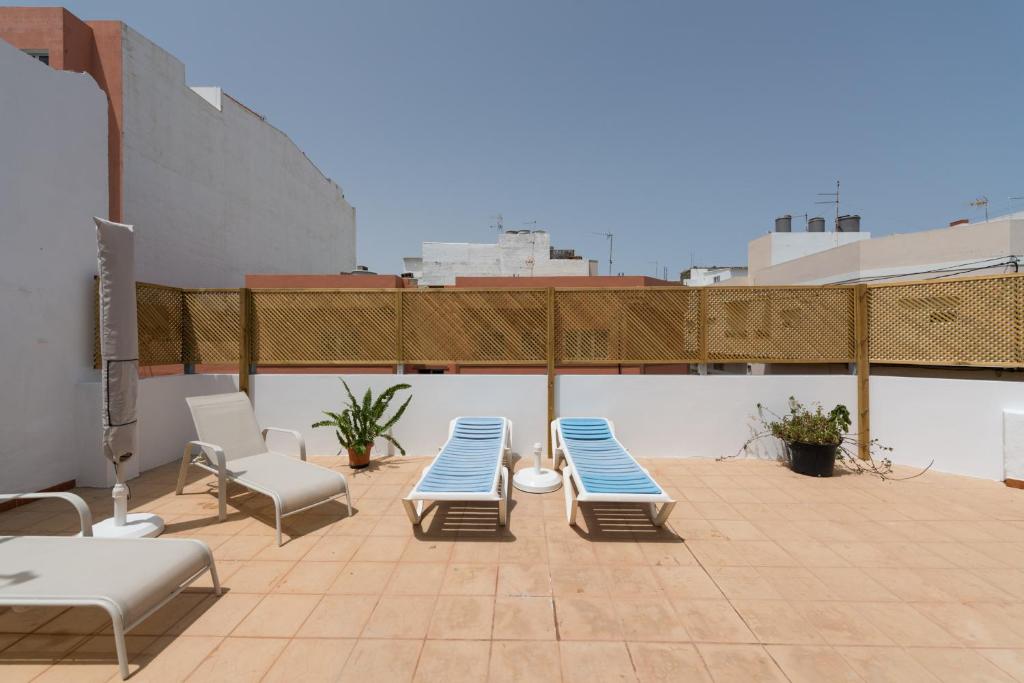 un patio con sillas azules y blancas en el techo en Private Solarium - 2BR House Near the Airport, en Vecindario