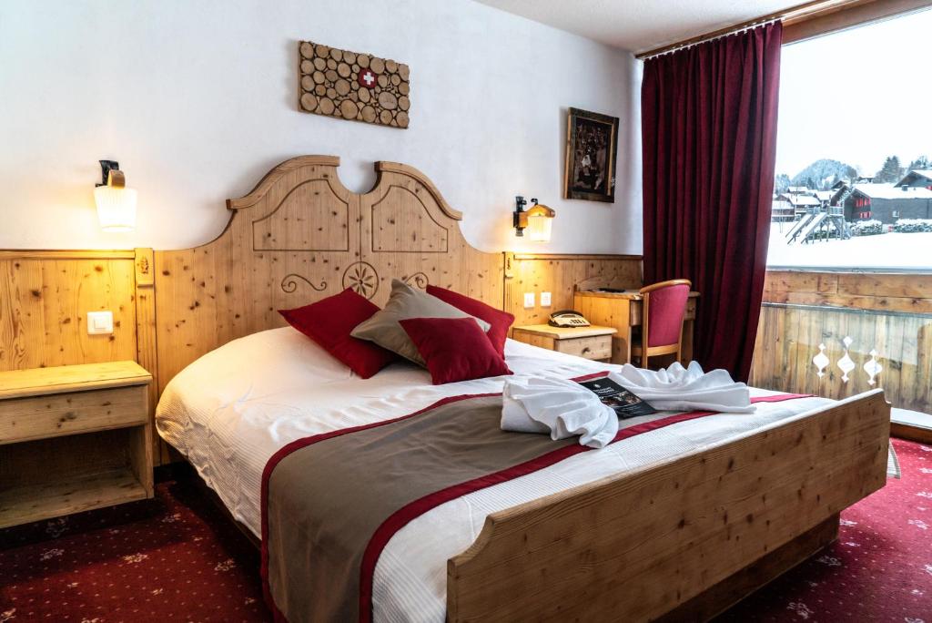 - une chambre avec un grand lit et des oreillers rouges dans l'établissement Hôtel Le Relais Alpin, à Les Mosses