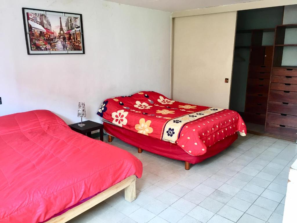 una camera con due letti e un piumone rosso di Casa Alsacia a Guadalajara
