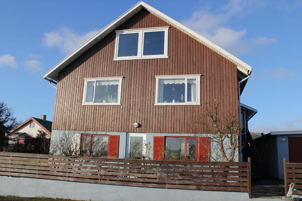 a large wooden house with red doors and windows at Lejligheder p&aring; Heygsmannavegur 15 in T&oacute;rshavn