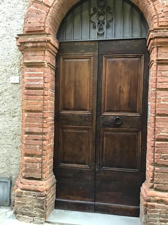 eine große Holztür in einem Backsteingebäude in der Unterkunft La Rocca in Sinalunga