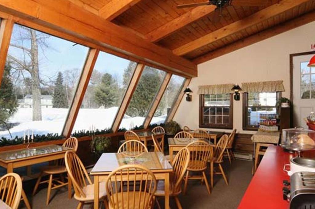 una sala da pranzo con tavoli, sedie e finestre di Old Field House a North Conway