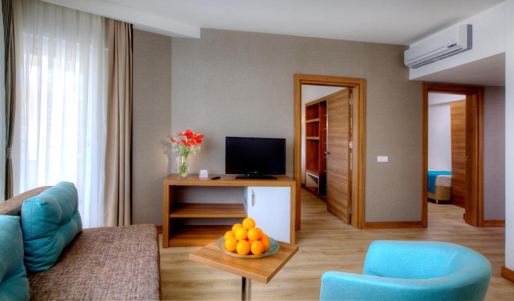 a living room with a couch and a table with a bowl of oranges at Grand Park Lara Hotel in Lara