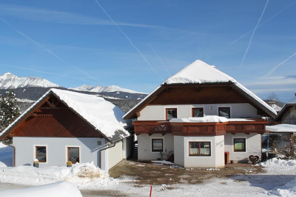 une maison recouverte de neige avec des montagnes en arrière-plan dans l'établissement Neumann Ferienwohnung Fanning, à Mariapfarr