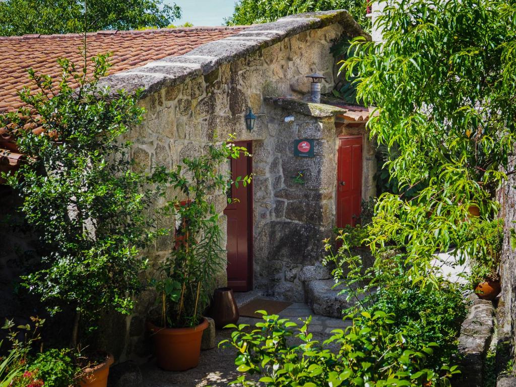 a stone house with a red door and some plants at Casa Das Videiras in Soajo