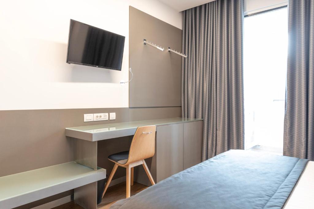 A compact bedroom combines a bed, wall-mounted television and built-in desk.